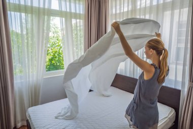 Genç bayan hizmetçi otel odasında yatak değiştiriyor.