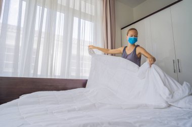 Coronavirüs karantinası nedeniyle tıbbi maske takan genç kadın hizmetçi COVID 19 Değişen Yatak Odası