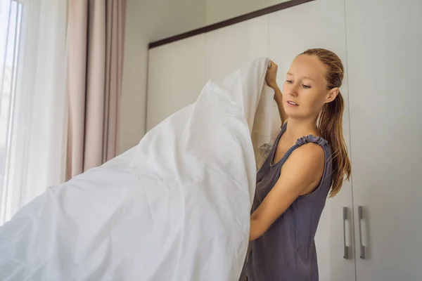 Joven ama de llaves femenina cambiando la cama en la habitación del hotel — Foto de Stock