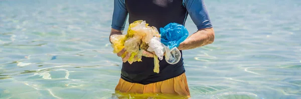 Ο άνθρωπος συλλέγει πακέτα από την όμορφη γαλαζοπράσινη θάλασσα. Παραντάις ρύπανση. Το πρόβλημα των απορριφθέντων σκουπιδιών στην άμμο της παραλίας που προκαλείται από την ανθρωπογενή ρύπανση και το περιβάλλον, εκστρατεία για να — Φωτογραφία Αρχείου