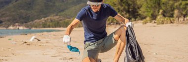 Eldivenli adam denizi kirleten plastik torbalar alıyor. İnsan yapımı kirlilik ve çevresel kirliliğin yol açtığı kumsala çöp dökme sorunu, konsept olarak gönüllü temizleme kampanyası