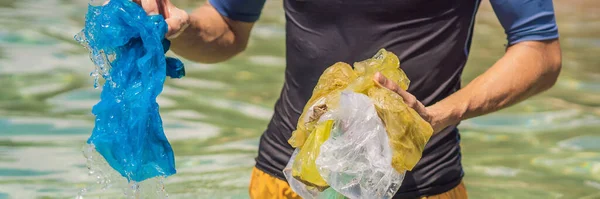El hombre recoge paquetes del hermoso mar turquesa. Paraíso contaminación de la playa. Problema de la basura derramada basura basura en la arena de la playa causada por la contaminación causada por el hombre y el medio ambiente, campaña para —  Fotos de Stock