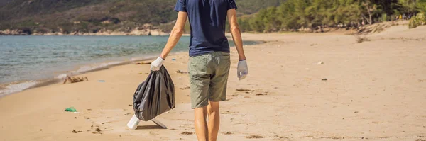 O homem de luvas pega em sacos de plástico que poluem o mar. Problema do lixo derramado lixo lixo na areia da praia causada pela poluição provocada pelo homem e ambiental, campanha para limpar voluntário em conceito — Fotografia de Stock