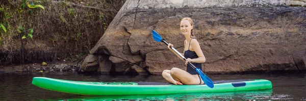 Side view picture of a woman sitting and relaxing on the sup board. Surfer woman resting BANNER, LONG FORMAT — Stock Photo, Image