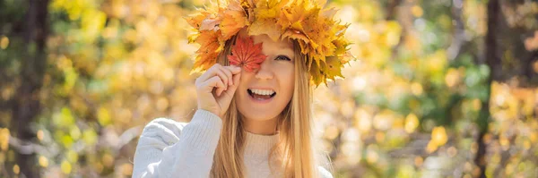 Stile di vita all'aperto primo piano ritratto di affascinante bionda giovane donna che indossa una corona di foglie autunnali. Sorridente, passeggiando nel parco autunnale. Indossa un pullover elegante a maglia. Ghirlanda di foglie d'acero — Foto Stock