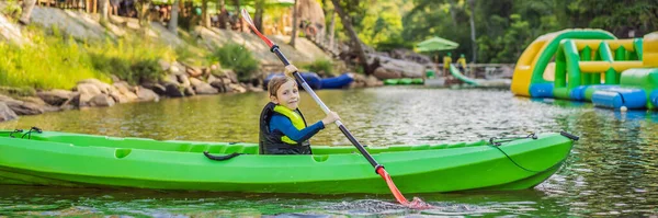 Glad ung pojke som håller paddla i en kajak på floden, njuter av en härlig sommardag BANNER, LONG FORMAT — Stockfoto