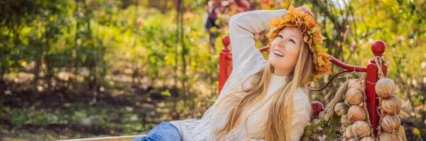 Açık hava yaşam tarzı samanlıkta sonbahar yapraklarından bir çelenk takan çekici sarışın genç bir kadının yakın portresi. Şık örülü kazak giyiyor. Akçaağaç çelengi BANNER 'dan ayrılıyor.