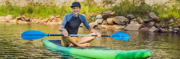 Radosny człowiek trenuje deskę SUP w rzece w słoneczny poranek. Wstań paddle boarding - niesamowite aktywnego wypoczynku na świeżym powietrzu BANNER, LONG FORMAT — Zdjęcie stockowe