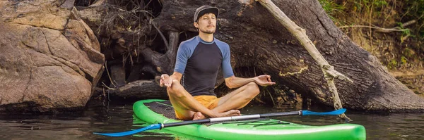 在一个大河上的日出时分，一个人在SUP板上练习瑜伽。站立板登船-大自然中令人敬畏的积极娱乐活动，长形 — 图库照片