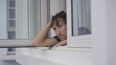 Zorunlu karantinada genç bir adam. İki hafta boyunca bir odada kalıyor. Uzun süre tıraş olmadı, stresli ve üzgün. Pencerenin yanına oturur ve dışarı bakar. Karantinada kalıyoruz.