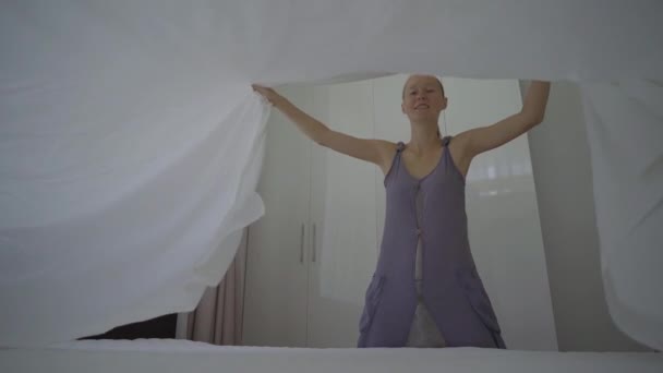 Повільний знімок молодої жінки змінює постільну білизну в кімнаті — стокове відео