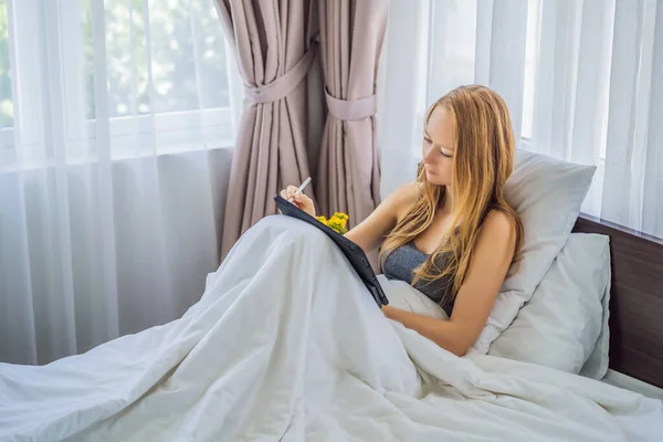 Vrouw tekent op tablet met stylus in bed — Stockfoto