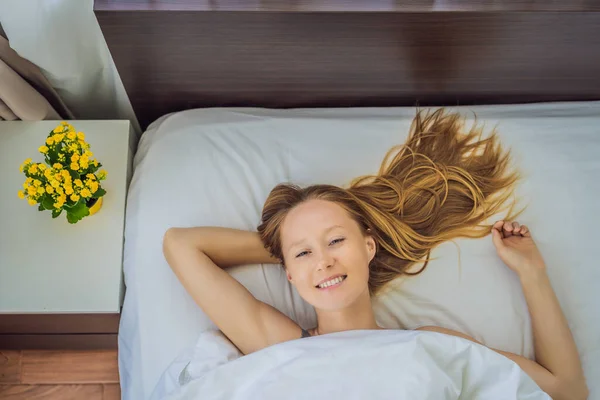 Slaap zonder kussen. Jonge vrouw die in bed slaapt zonder kussen. Portret van een mooie vrouw rustend op een comfortabel bed zonder een kussen in wit beddengoed in lichte slaapkamer in de ochtend. Mensen — Stockfoto