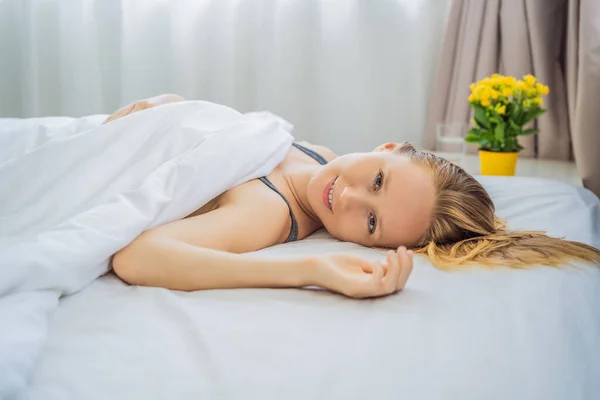 Duerme sin almohada. Mujer joven durmiendo en la cama sin almohada. Retrato de una hermosa hembra descansando en una cama cómoda sin almohada en una cama blanca en un dormitorio ligero por la mañana. Gente — Foto de Stock