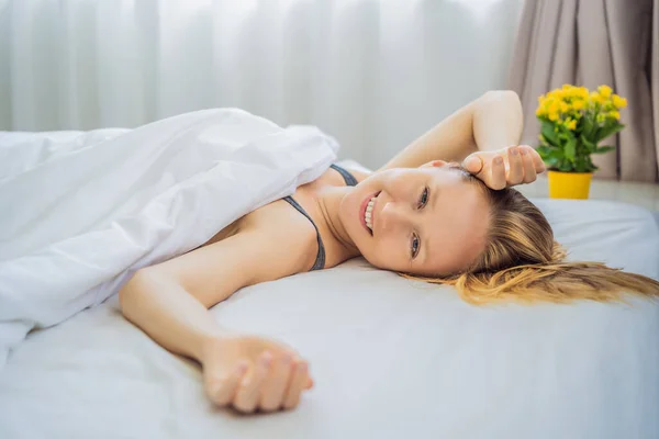 Duerme sin almohada. Mujer joven durmiendo en la cama sin almohada. Retrato de una hermosa hembra descansando en una cama cómoda sin almohada en una cama blanca en un dormitorio ligero por la mañana. Gente — Foto de Stock