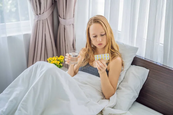 Γυναίκα που πάσχει από ασθένεια ή αϋπνία ξαπλωμένη στο κρεβάτι έτοιμη να πάρει ένα δισκίο φαρμακευτική αγωγή — Φωτογραφία Αρχείου