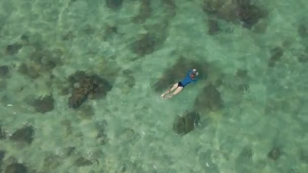 4K toma de cámara lenta aérea de una mujer joven buceando en un mar azul claro — Vídeos de Stock