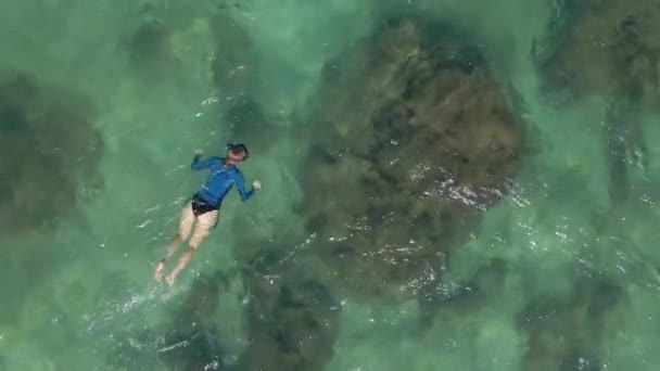 Açık mavi deniz suyunda şnorkelle yüzen genç bir kadının 4K hava yavaş çekimi. — Stok video