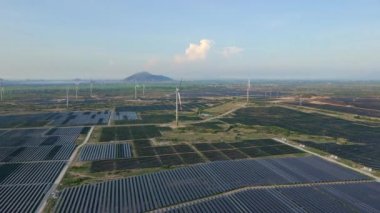 Büyük bir tarlada rüzgar türbinleriyle karıştırılmış devasa bir güneş enerjisi santralinin havadan çekimi. Güneş enerjisi ve rüzgardan elektrik üretimi. Yeşil enerji ve sıfır emisyon kavramı