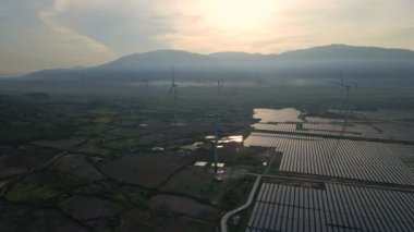 Büyük bir tarlada rüzgar türbinleriyle karıştırılmış devasa bir güneş enerjisi santralinin havadan çekimi. Güneş enerjisi ve rüzgardan elektrik üretimi. Yeşil enerji ve sıfır emisyon kavramı