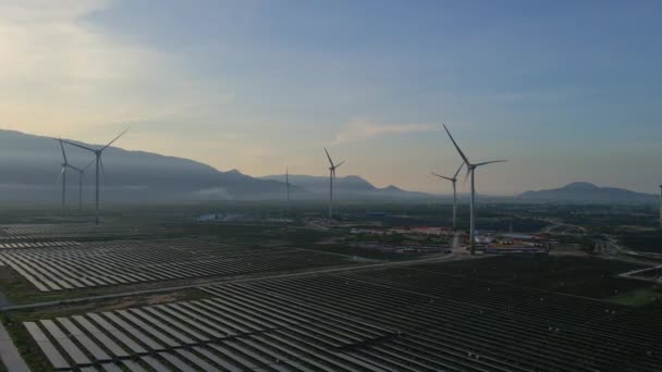 Légi felvétel egy hatalmas naperőműről, szélturbinákkal keverve egy nagy mezőn. Villamosenergia-termelés nap- és szélenergiából. Zöld energia és kibocsátásmentes koncepció — Stock videók