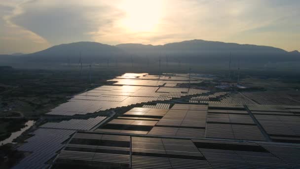 Toma aérea de una enorme planta de energía solar mezclada con turbinas eólicas en un gran campo. Generación de electricidad a partir de energía solar y eólica. Energía verde y concepto de cero emisiones — Vídeos de Stock