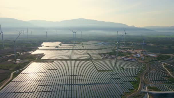 Tiro aéreo de uma enorme usina de energia solar misturada com turbinas eólicas em um grande campo. Geração de eletricidade a partir de energia solar e eólica. Conceito de energia verde e emissões zero — Vídeo de Stock