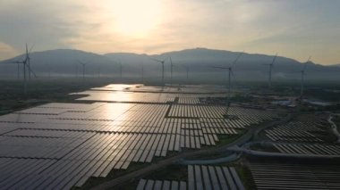 Büyük bir tarlada rüzgar türbinleriyle karıştırılmış devasa bir güneş enerjisi santralinin havadan çekimi. Güneş enerjisi ve rüzgardan elektrik üretimi. Yeşil enerji ve sıfır emisyon kavramı