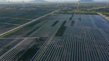 Büyük bir tarlada rüzgar türbinleriyle karıştırılmış devasa bir güneş enerjisi santralinin havadan çekimi. Güneş enerjisi ve rüzgardan elektrik üretimi. Yeşil enerji ve sıfır emisyon kavramı