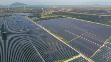 Büyük bir tarlada rüzgar türbinleriyle karıştırılmış devasa bir güneş enerjisi santralinin havadan çekimi. Güneş enerjisi ve rüzgardan elektrik üretimi. Yeşil enerji ve sıfır emisyon kavramı