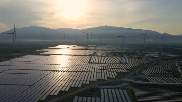 Letecký záběr obrovské solární elektrárny smíchané s větrnými turbínami na velkém poli. Výroba elektřiny ze sluneční energie a větru. Koncept zelené energie a nulových emisí — Stock video