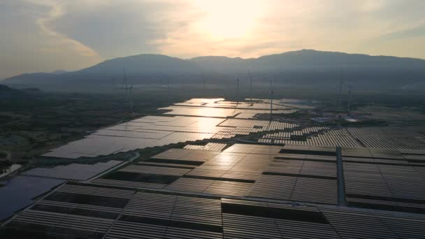 Büyük bir tarlada rüzgar türbinleriyle karıştırılmış devasa bir güneş enerjisi santralinin havadan çekimi. Güneş enerjisi ve rüzgardan elektrik üretimi. Yeşil enerji ve sıfır emisyon kavramı — Stok video