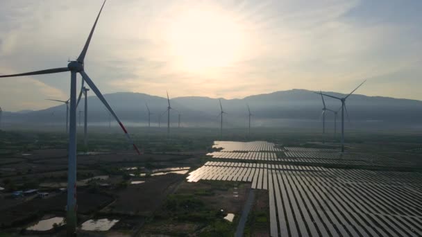 Letecký záběr obrovské solární elektrárny smíchané s větrnými turbínami na velkém poli. Výroba elektřiny ze sluneční energie a větru. Koncept zelené energie a nulových emisí — Stock video