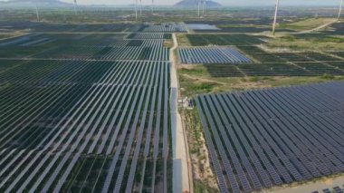 Büyük bir tarlada rüzgar türbinleriyle karıştırılmış devasa bir güneş enerjisi santralinin havadan çekimi. Güneş enerjisi ve rüzgardan elektrik üretimi. Yeşil enerji ve sıfır emisyon kavramı