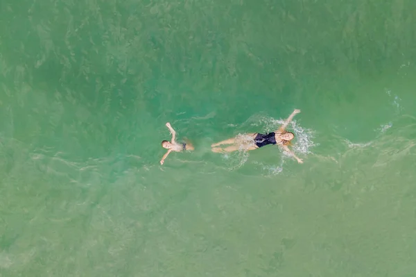 Máma a syn v čisté tyrkysové vodě na pláži. Zobrazení dronů — Stock fotografie