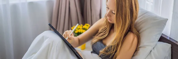 女人在床上用手写笔在石碑上画，长形 — 图库照片
