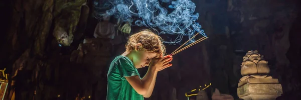 Niño rezando en un templo budista sosteniendo incienso Cueva Huyen Khong con santuarios, montañas de mármol, Vietnam BANNER, FORMATO LARGO — Foto de Stock