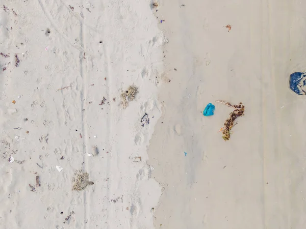 Песчаный пляж с пластиковым мусором и медицинскими отходами на тропическом пляже с изумрудным чистым морем - фото с воздуха, сделанное дроном — стоковое фото