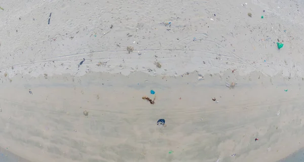 Sandy beach with Plastic garbage and medical waste materials in tropical beach with emerald clear sea - Aerial top view photo taken by drone