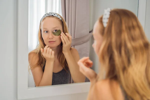 Mirror reflection smiling woman applying hydrogel eye care patches, moisturizing skin under eyes, enjoying skincare procedures