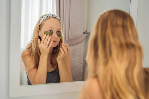 Spegel reflektion leende kvinna applicera hydrogel ögonvård fläckar, återfuktande hud under ögonen, njuta av hudvård förfaranden — Stockfoto