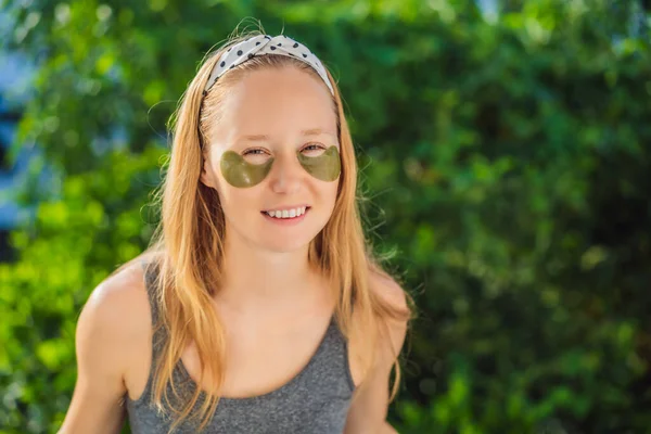 Gülümseyen kadın hidrojene göz bandı yapıştırıyor, göz altındaki deriyi nemlendiriyor, cilt bakımı ameliyatlarından zevk alıyor.