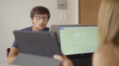 Arka planda mutfak olan genç bir kadın ve erkek oturma odalarında çalışıyorlar. İkisi de Covid-19 kısıtlamalarından dolayı uzaktan çalışmak zorunda. Covid-19 salgın konsepti