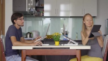 Arka planda mutfak olan genç bir kadın ve erkek oturma odalarında çalışıyorlar. İkisi de Covid-19 kısıtlamalarından dolayı uzaktan çalışmak zorunda. Covid-19 salgın konsepti