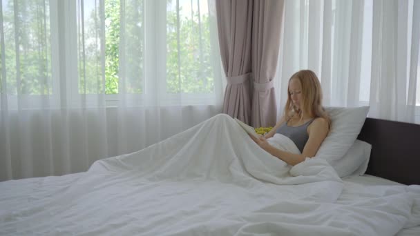 Genç bir kadın yatakta yatarken deftere bir şeyler yazıyor. — Stok video