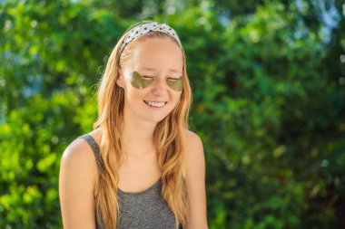 Gülümseyen kadın hidrojene göz bandı yapıştırıyor, göz altındaki deriyi nemlendiriyor, cilt bakımı ameliyatlarından zevk alıyor.
