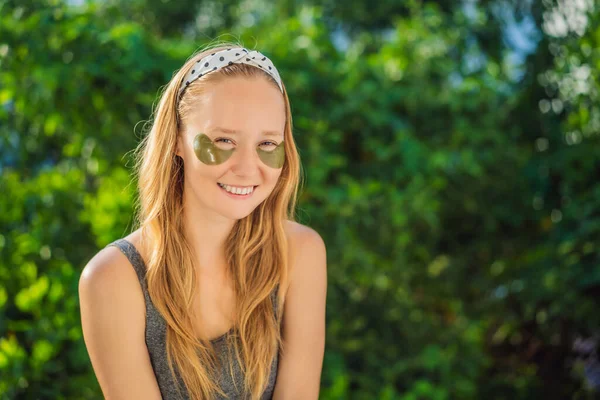 Smiling woman applying hydrogel eye care patches, moisturizing skin under eyes, enjoying skincare procedures — Stock Photo, Image