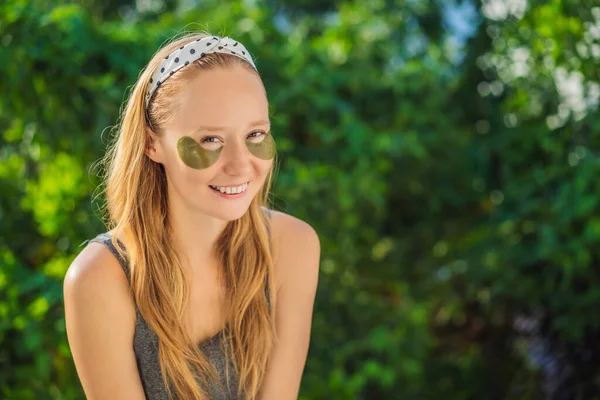 Усміхнена жінка застосовує гідрогелеві латки для догляду за очима, зволожуючи шкіру під очима, насолоджуючись процедурами скінкарда — стокове фото