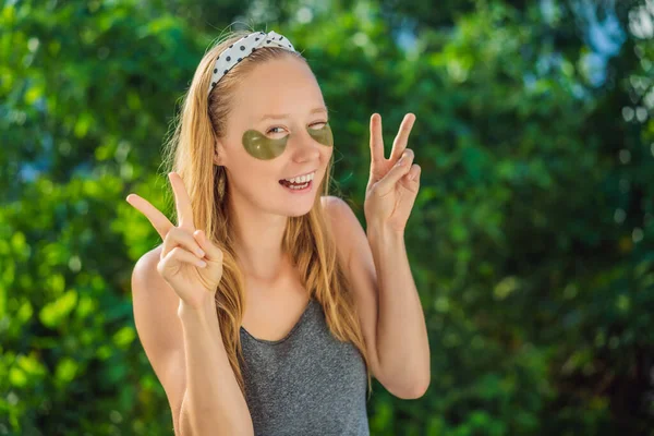 Femme souriante appliquant des patchs hydrogel pour les yeux, hydratant la peau sous les yeux, bénéficiant de procédures de soins de la peau — Photo