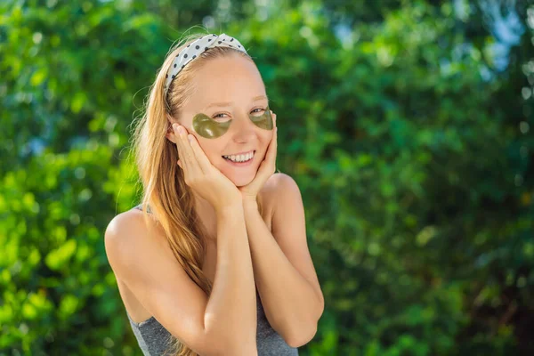 Smiling woman applying hydrogel eye care patches, moisturizing skin under eyes, enjoying skincare procedures